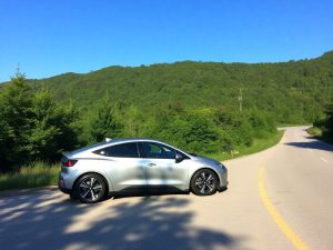 Masina electrica moderna pe un drum scenic.