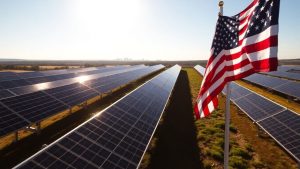 Panouri solare în fața unui oraș american sub soare.